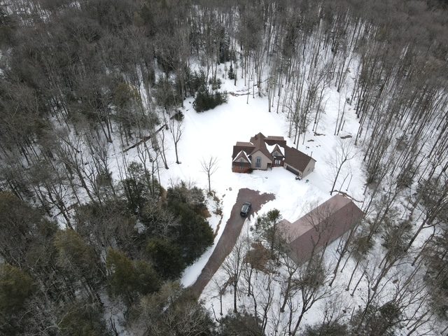 Aerial overview of the property in winter showing house, driveway, pole barn, and wooded acreage