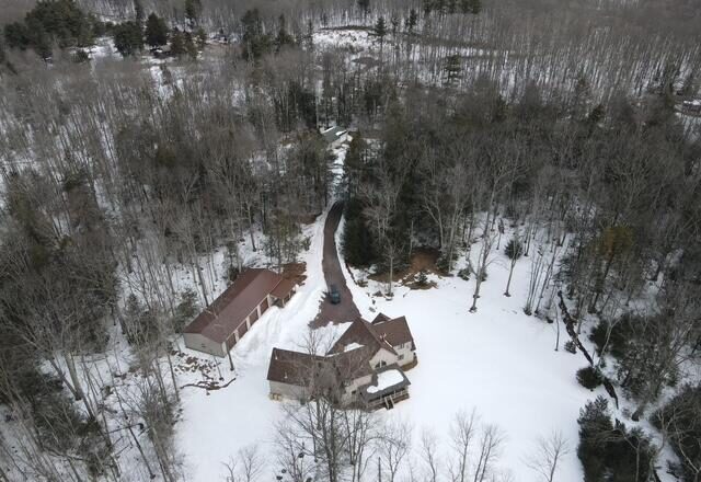 Wide aerial showing wooded acreage and house in winter